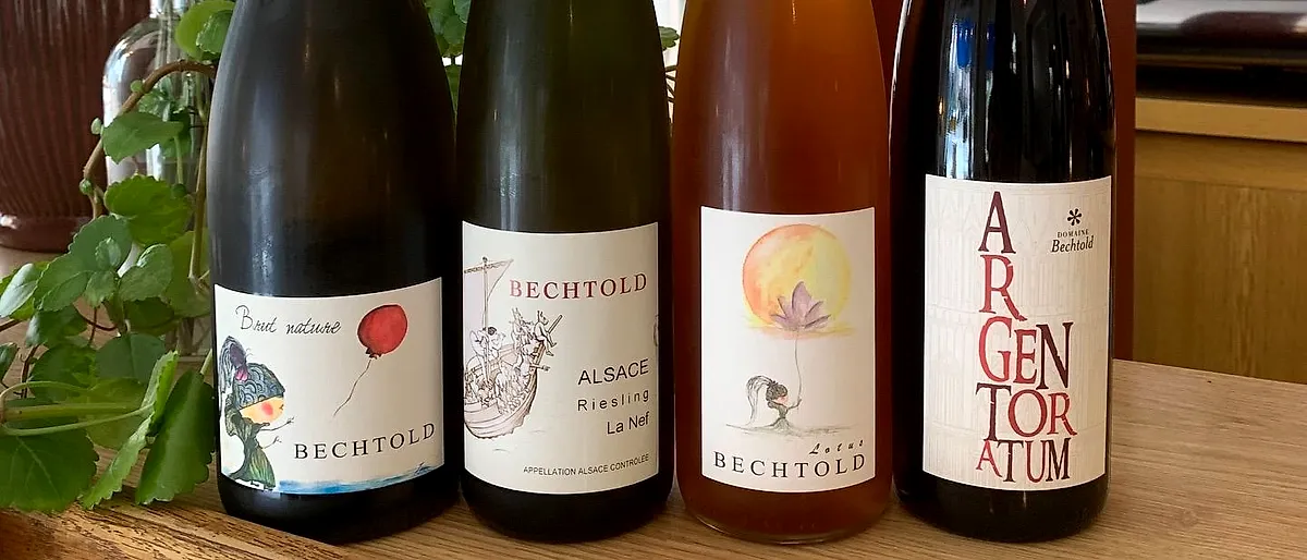 Bouteilles de vin nature sur le comptoir, devant le mur rouge du Café